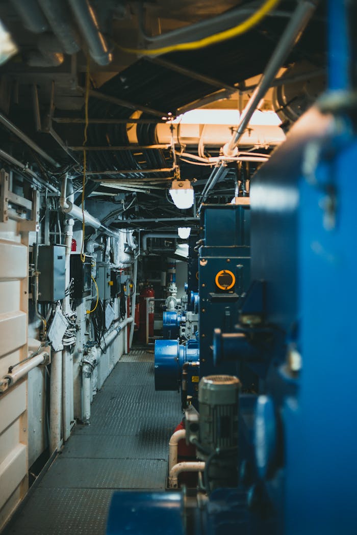 A detailed view of industrial machinery and pipes in a maintenance corridor.